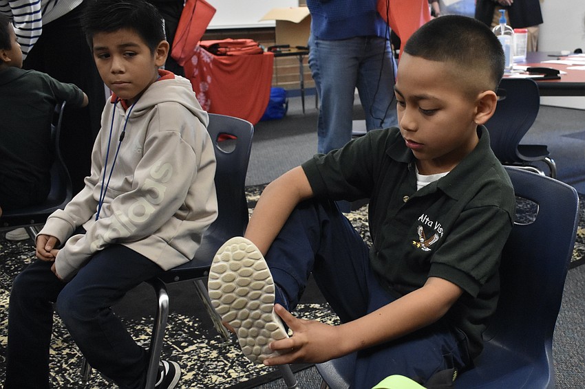 Kidnergartener Salvador De La Cruz watches as kindergartener Juan Pabon Argote tries on a new pair of shoes.