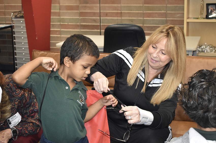 Kindergartener David Furlow receives a bag with his new shoes, from Dawn Merila.