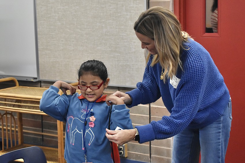 Kindergartener Daisy Castillo Ortiz receives a bag with her new shoes from Tina Russell.