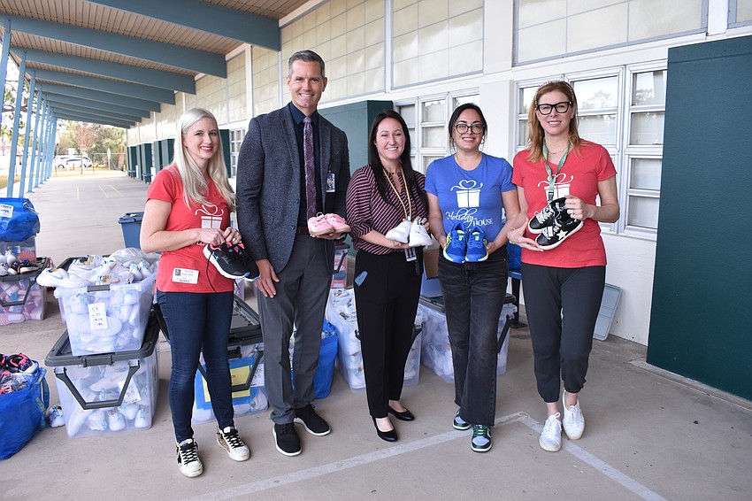 Holiday House co-founder Jenni Infanti, Superintendent of Schools Terry Connor, Principal Mindy Long, and Holiday House co-founder Sepi Ackerman and board member Hilary Yunis stand beside the shoes set for distribution.