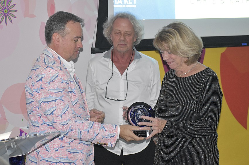 Board chair Eric Fleming presents an award to Kathy Elliott and husband Chris Elliott, who were honored with the Siesta Selfless award for using their artistic and marketing skills to create signage for Chamber events, and volunteering at the Crystal Classic.