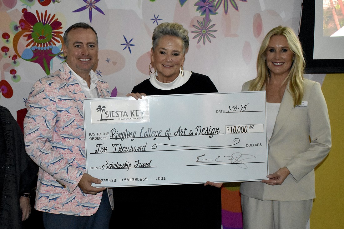 Eric Fleming, board chair of Siesta Key Chamber, presents a check to Lora Wey and Dana Dalpra for funds raised during the Siesta Key Crystal Classic.