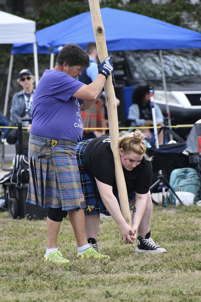 Becky Wissink helps Julianne Durante take hold of the caber.