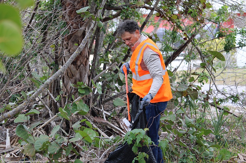 Chris Moneuse works among the mangroves to carefully remove storm debris.