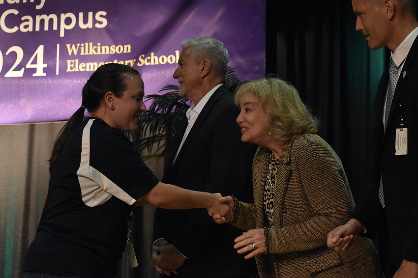 Stefanie Lynch accepts the award, shaking hands with officials including school board members Tom Edwards and Robyn Marinelli, and Superintendent of Schools Terry Connor.