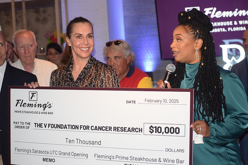 Dick Vitale's daughter, Terri Vitale, accepts a $10,000 check from Sheilina Henry, president of Fleming's Steakhouse and Wine Bar, to benefit the V Foundation for Cancer Research during a soft opening event Saturday.
