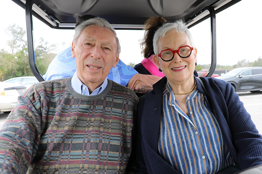 Sheldon and Lynne Sandman take a golf cart ride from the Ora's parking lot up to the event.