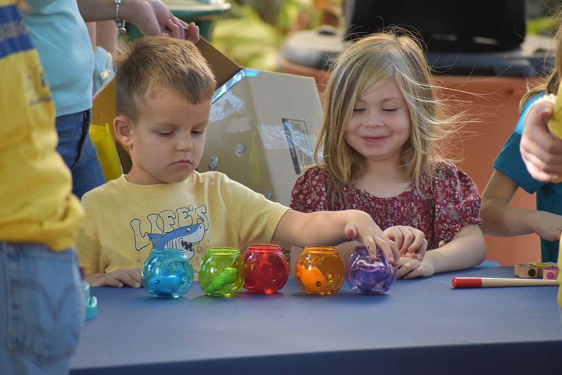 Mark Sumegi, 4, sorts fish into different colored bowls, as Violet Moore, 3, watches.