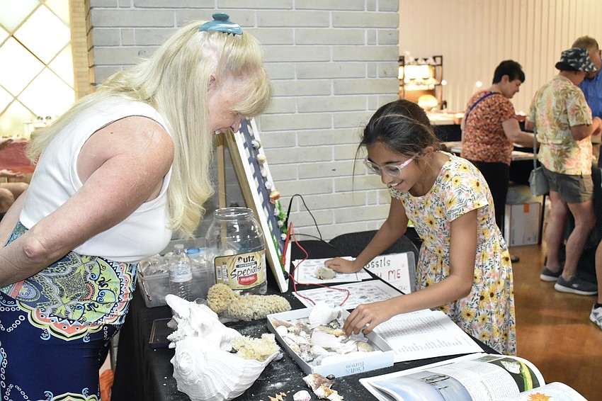 Kathy Desrochers welcomes Aarya Strnad, 11, at the education table.