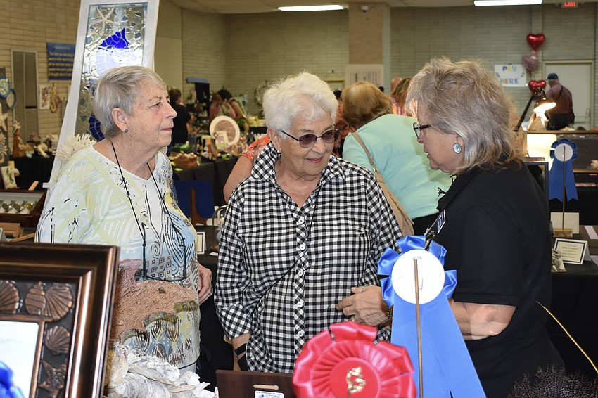 Connie Knapp, Judy Farmer and exhibitor Guelda Woolridge talk by the display of First Place creations.