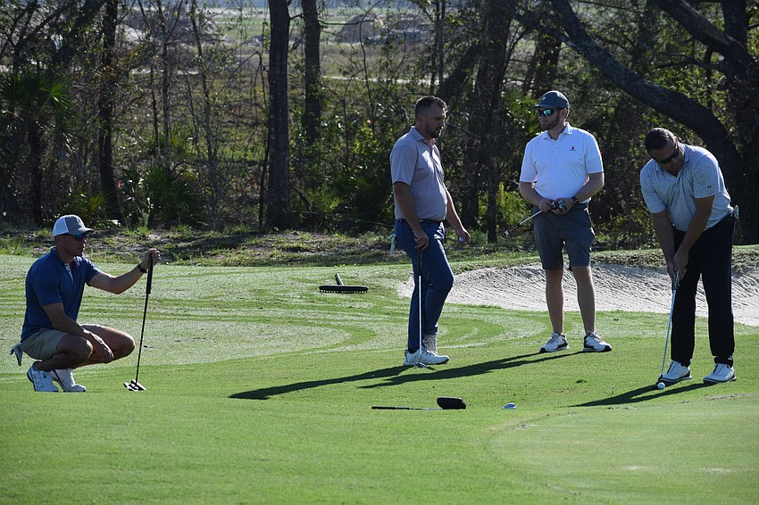 Jason Mitchell lines up a putt as Nick Irle, Curtis Ross and Garrett Shinn watch during the Lakewood Ranch Community Foundation event at Calusa Country Club Monday.