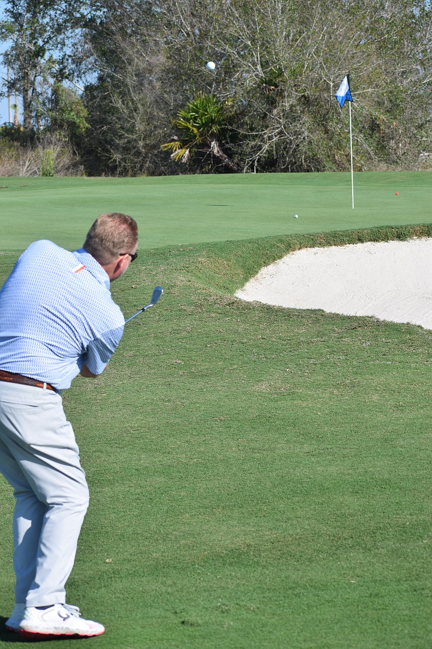 Scott MacDonald tries to chip his ball closer to the pin than his playing partners during the Lakewood Ranch Community Foundations charity scramble on Monday morning at Calusa Country Club.