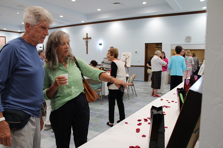 Kathy Surma and Jorge Varcelotti admire an oil painting by Richard Boyer at the 
