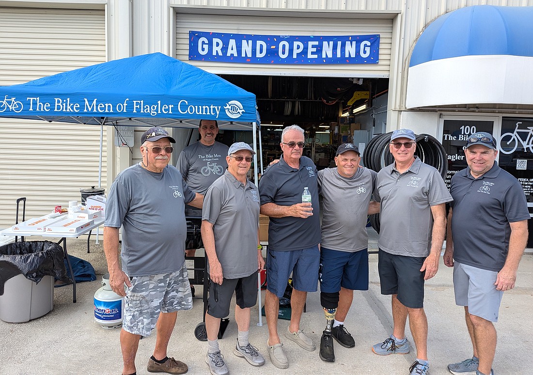 The Bike Men of Flagler County volunteers at the grand opening celebration at their new shop: Joe Golan, Marc Catoggio (behind the grill), Paul Wiederholt, John Carbone, Phil Lear, Steve Bingle and Sean Gear. Photo by Brent Woronoff