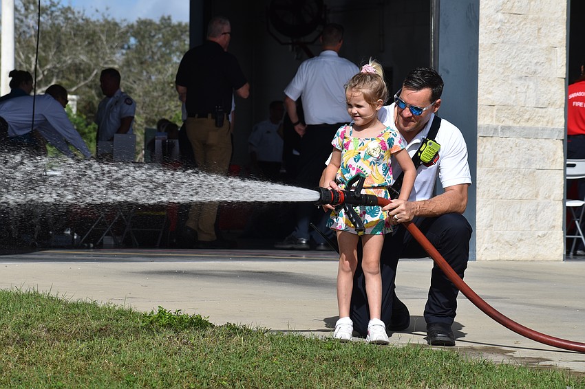 Bradenton's Brook Jackson, 5, the daughter of Lt. Dennis Jackson of Sarasota County, tries the fire hose with his help.
