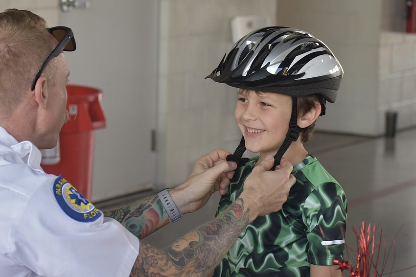 Lt. Jacob Siegel offers Sarasota's Ian Sweeney, 6, a bike helmet fitting.