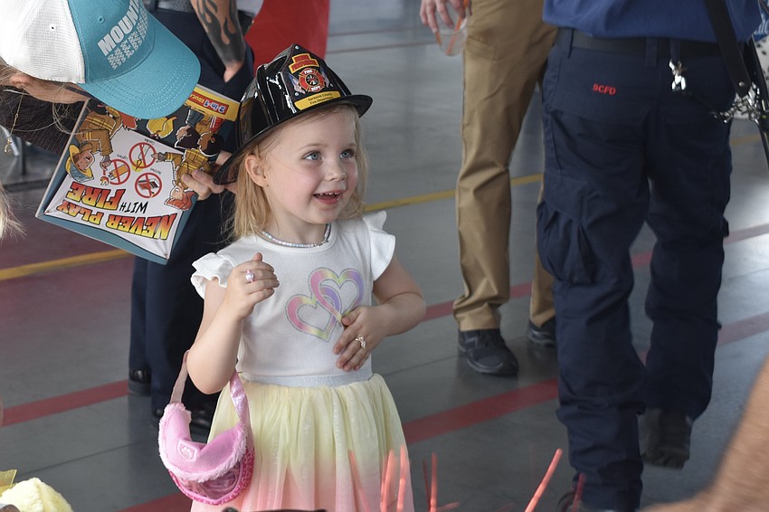 Sarasota's Kelly-Anne Shedd-Hartman visits with her daughter Orianna Hartman, 3, who tries on a fire helmet provided by Public Education Coordinator Michael Rodrigue. “She really wants to be a firefighter, so this is really exciting for us,” said her mom Kelly-Anne Shedd-Hartman.