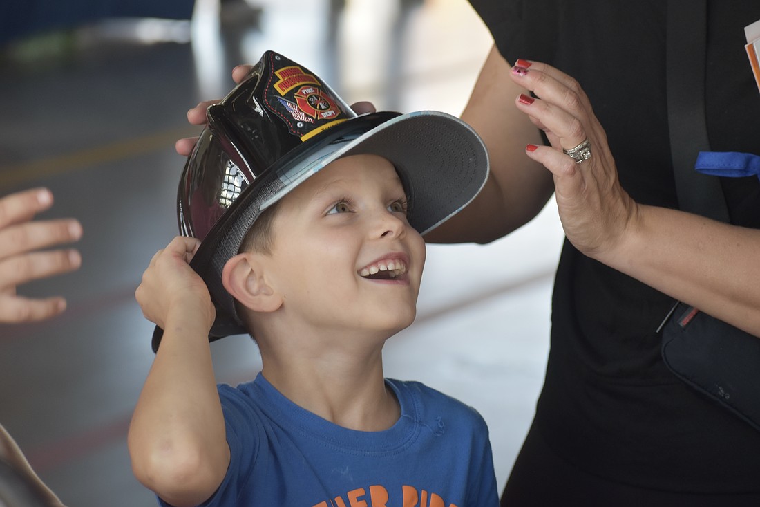 Sarasota's Clayton Lambert, 6, tries on a fire helmet with the help of his mother Megan Lambert.