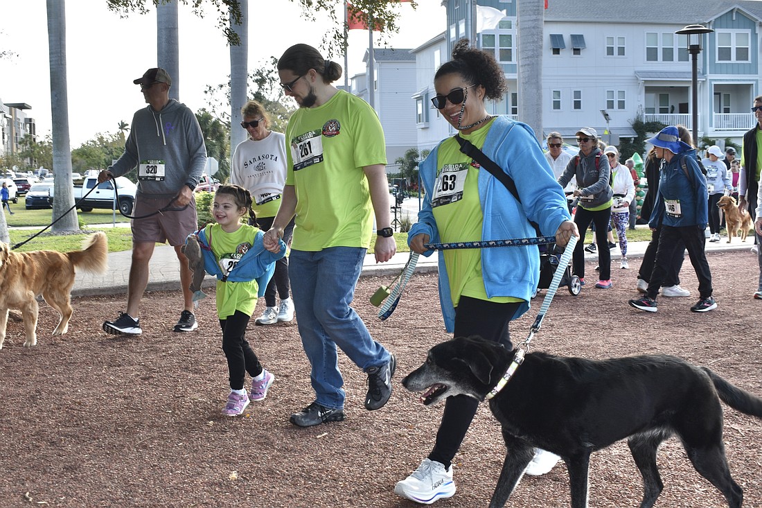 Lennox Abell, 5, her parents Logan and Lakesha Abell, and their dog Netalya, make their way along the walk.
