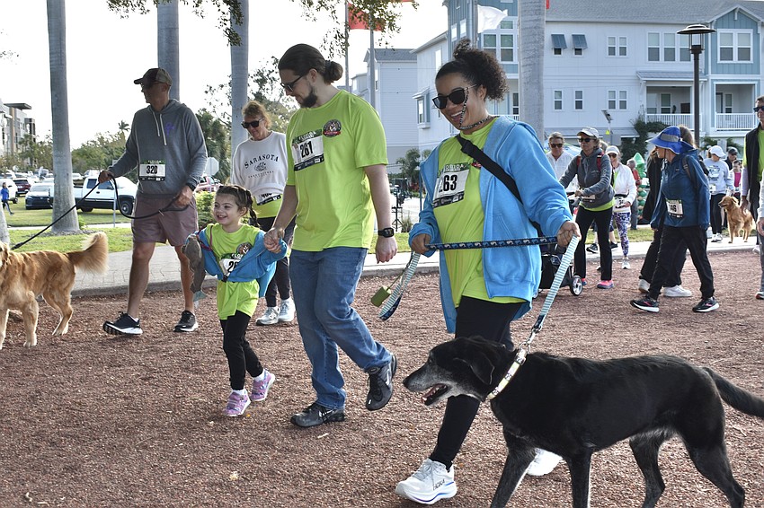 Lennox Abell, 5, her parents Logan and Lakesha Abell, and their dog Netalya, make their way along the walk.