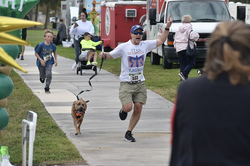Rhett Fledderman, 10 (left), Zuma, the first pup to finish the race, and Brett Keyser, approach the finish line.