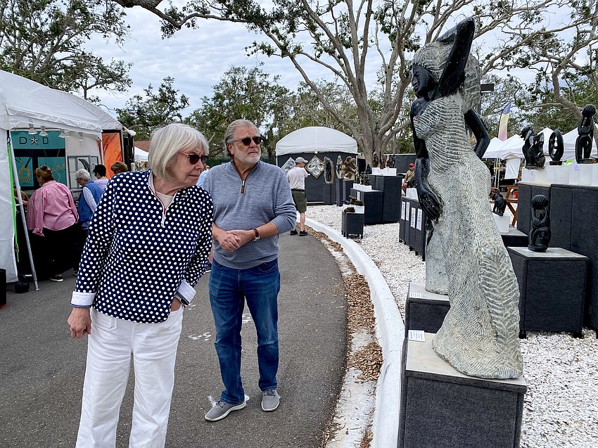 Madeline Rubenstein and Alan Goldman view a set of sculptures by Peter Rujuwa.