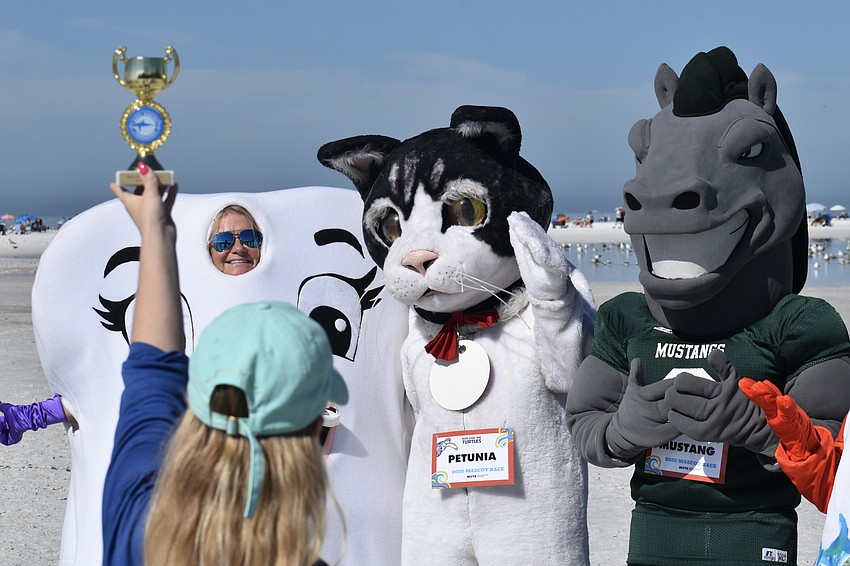 Mote's Kaitlyn Fusco holds out a trophy in front of Super Tooth from Varone Orthodontics, Petunia from Cat Depot, and the race's winner, Mustang from Lakewood Ranch High School.