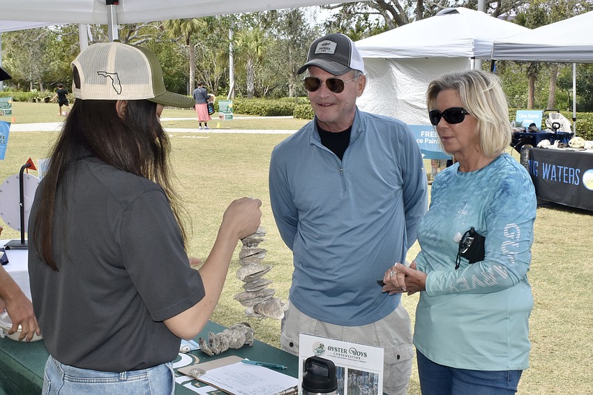 Oyster Boys Conservation volunteer Abby Hendershot discusses oyster gardens with attendees Gary Johnson and Vickie Vincent.