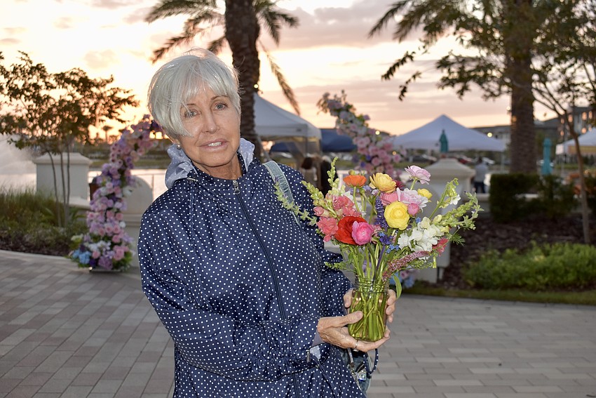 Waterside Place resident Tracy Wolf walks back home with a bouquet of flowers from Mindful Blooms Farm, which had a stand set up at the night market.