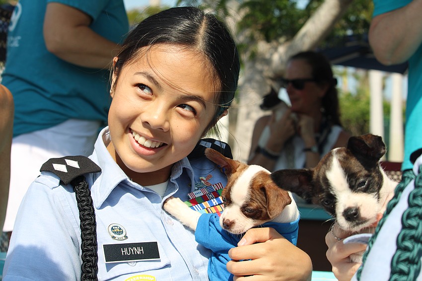 Emily Huynh, volunteering at the dog show with Sarasota Military Academy Prep, takes a moment to hold a puppy.