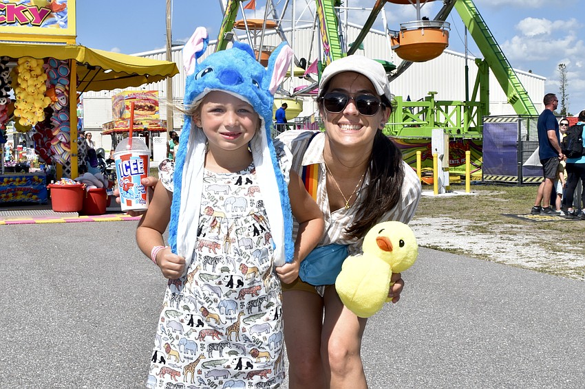 Emma Baird, 7, and her mom Sarah Anderson, explore while carrying some colorful new purchases from the fair.