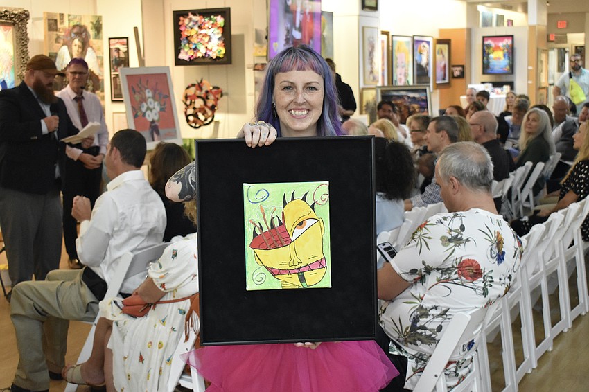 Megan Howell holds a work by resident Nick Rentschler depicting his past struggles.