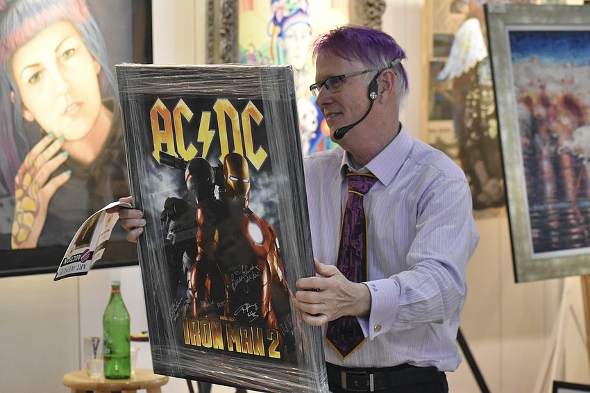 Paul Sykes holds up the autographed AC/DC poster donated by Sarasota resident and lead AC/DC singer Brian Johnson.