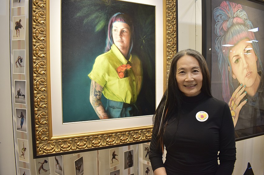 Li Jian Volk stands with the portrait she painted of Megan Howell.