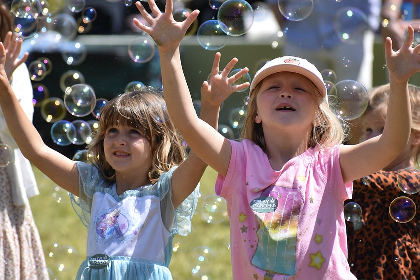 Gemma King, 5, and her sister Grace King, 7, welcome a flurry of bubbles in the bubble show.