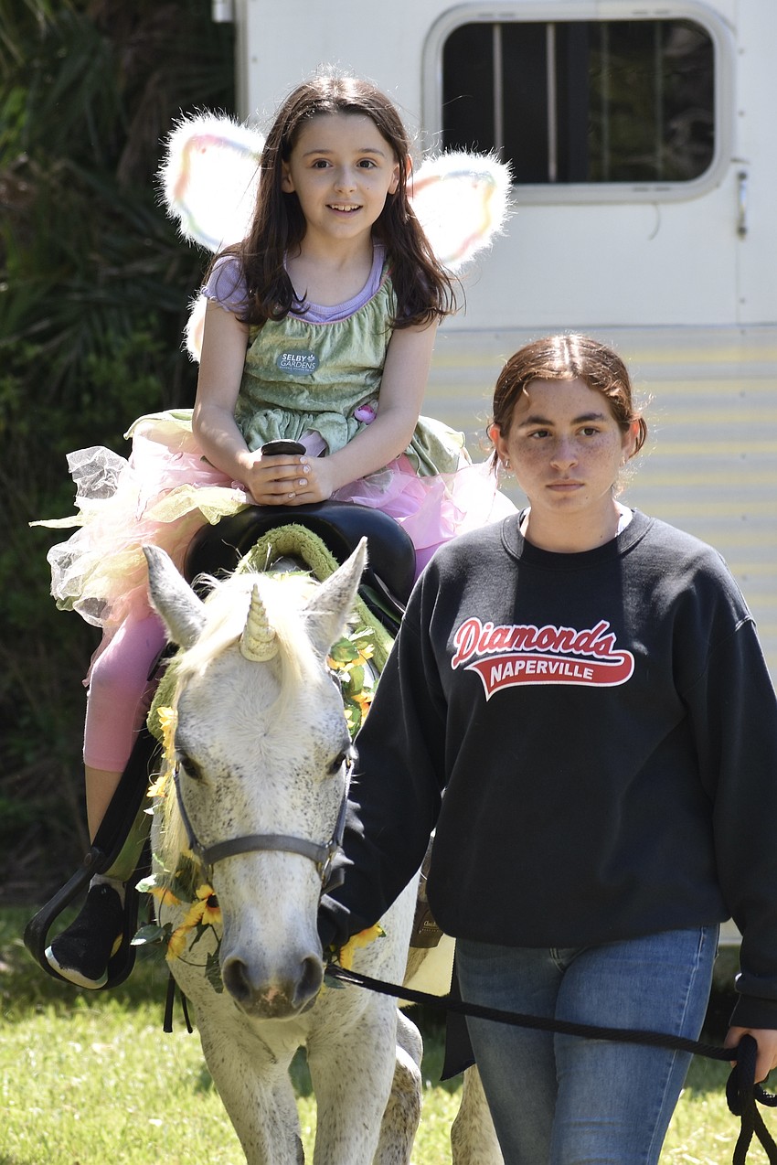Teigan Oakley, 7, rides a uniorn led by Rosaire's Riding Academy student Talia Balas.