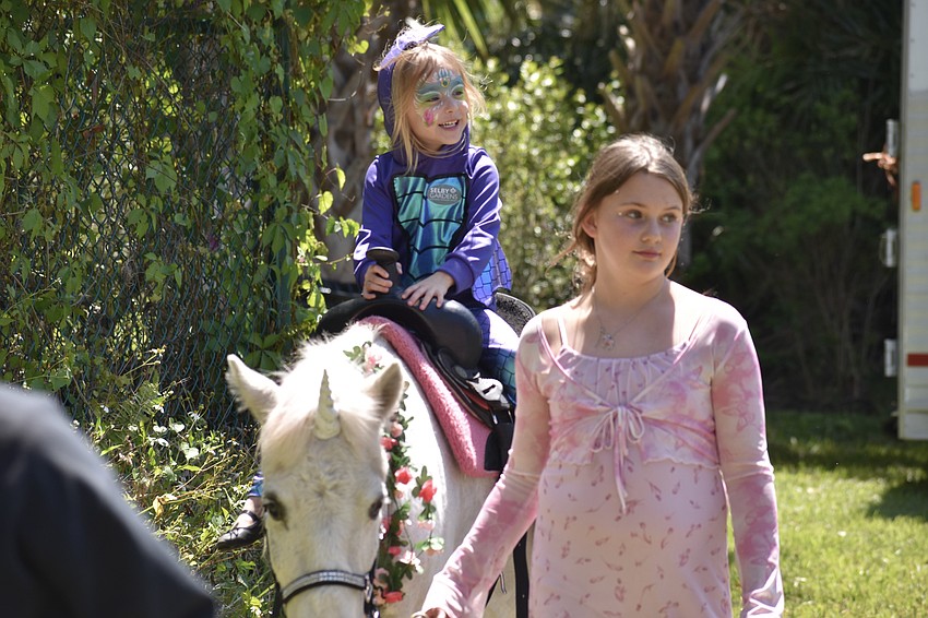 Abigail McDonough, 5, rides a unicorn led by Rosaire's Riding Academy student Tulula Schmidt.