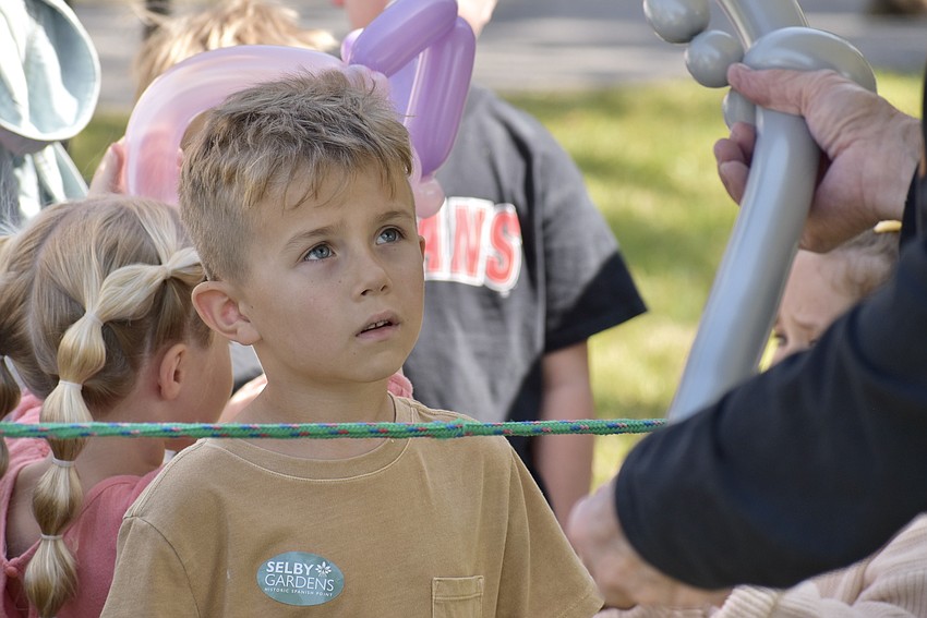 Matthew Elias, 6, watches as Greg Art folds a balloon.