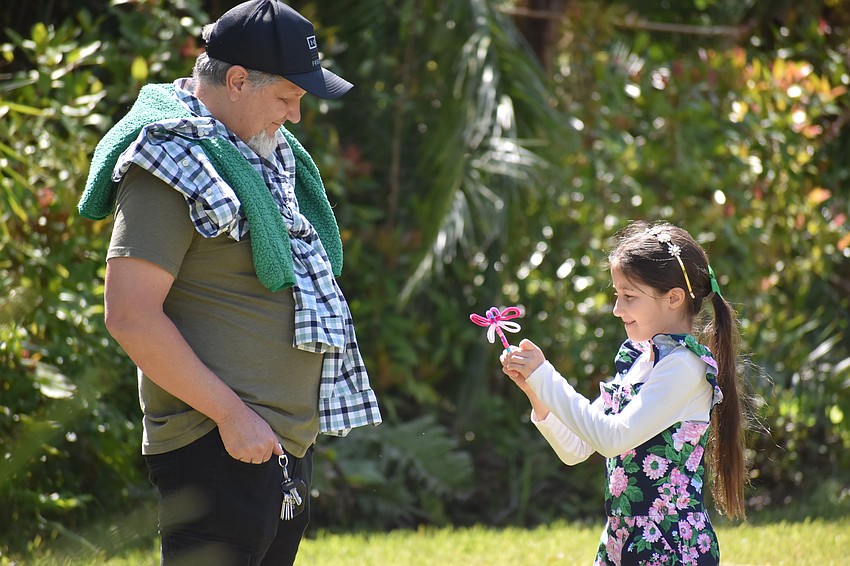 Rudy Ortega looks as his daughter Christina Ortega, 9, presents a craft.