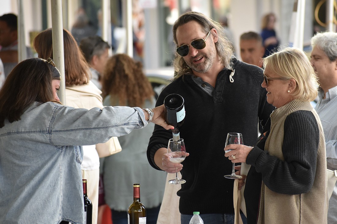 Laura George pours wine for Jason Campbell and his mother Colleen Campbell.