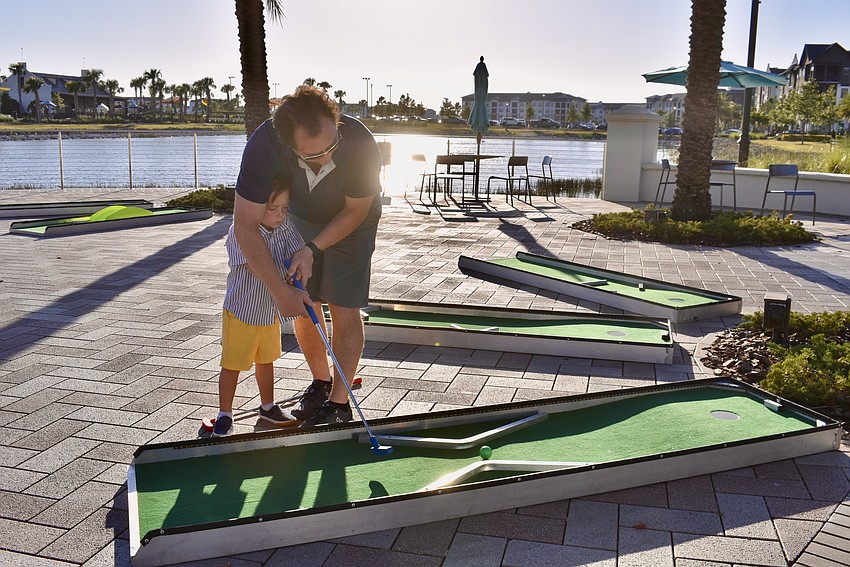 Country Club East's Cary Verasco teaches his 5-year-old son Jack how to putt.
