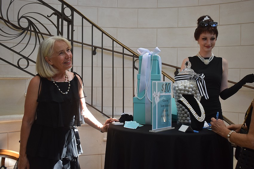 Kelly Colbert and Chloe Rusek stand at a table where guests guess how many pearls are in the jar.