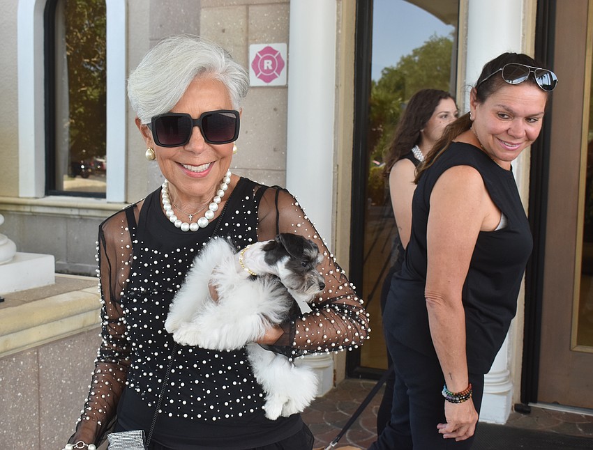 Alice Busch carries Bentley into Divas and Dogs as volunteer Evelyn Hernandez looks on.