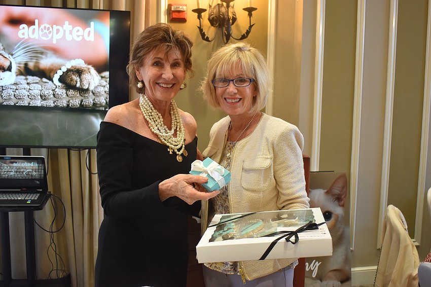 Susan Giroux, the Divas and Dogs chair, congratulates Vicki Fitzgerald, who won the golden pearl contest and a $500 reward.