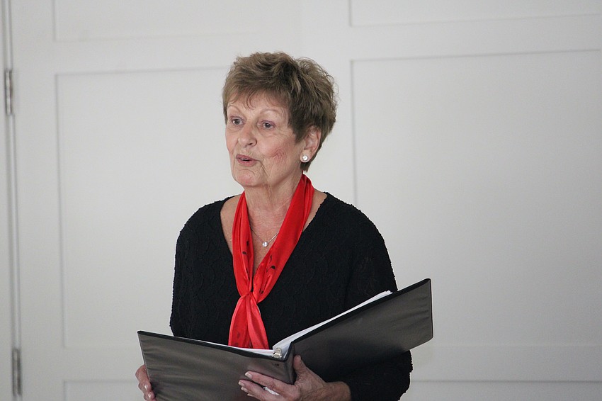 Sue Rinaldo introduces the setlist for the Key of Sea choir performance at the Player's Club.