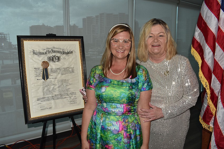 Sunny Westerberg and her mother Deborah Thomas pose next to the club's charter from 1926. Westerberg created a slideshow-style film about the history of the chapter, which was shown to members at the event.
