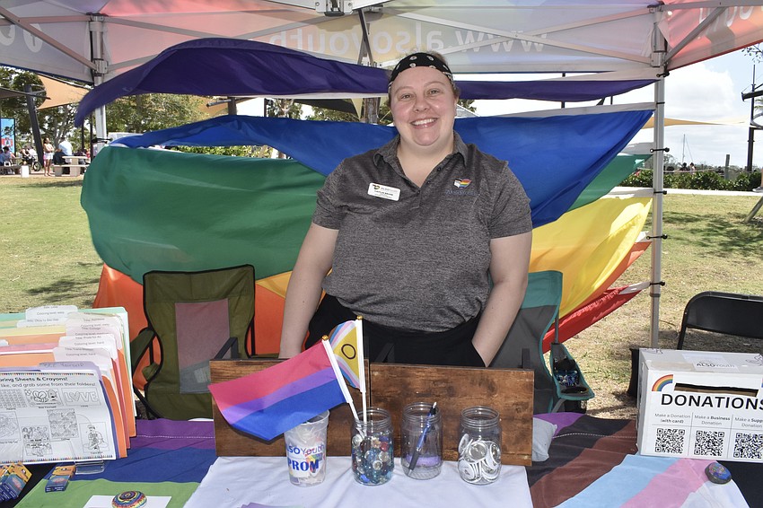 Caitlin Brunk of ALSO Youth, a support group for LGBTQ+ youth, stands at the organization's table.