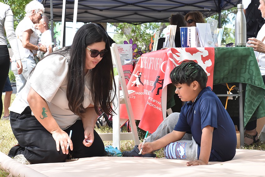 Caroline Muller and her cousin Abraham Evaristo, 6, add to the community canvas.