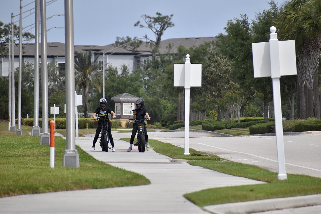 Two teens stop their electric bikes on White Eagle Boulevard near Eagle Trace.