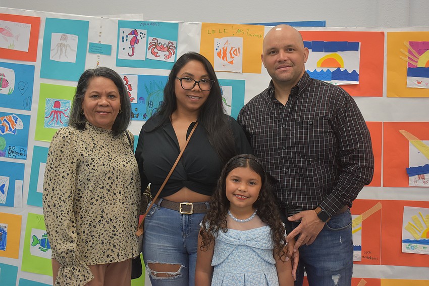 Coromoto Diaz, Anmi Petit, Jesus Acosta and second grader Alessia Acosta stand in front of the artwork made by the second graders.